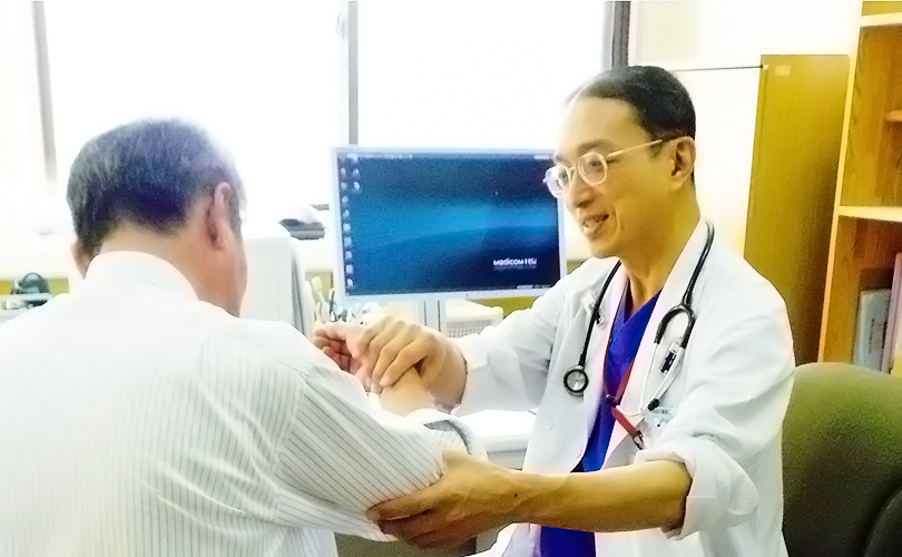 医師が高齢患者の腕を診察している医務室・診療空間